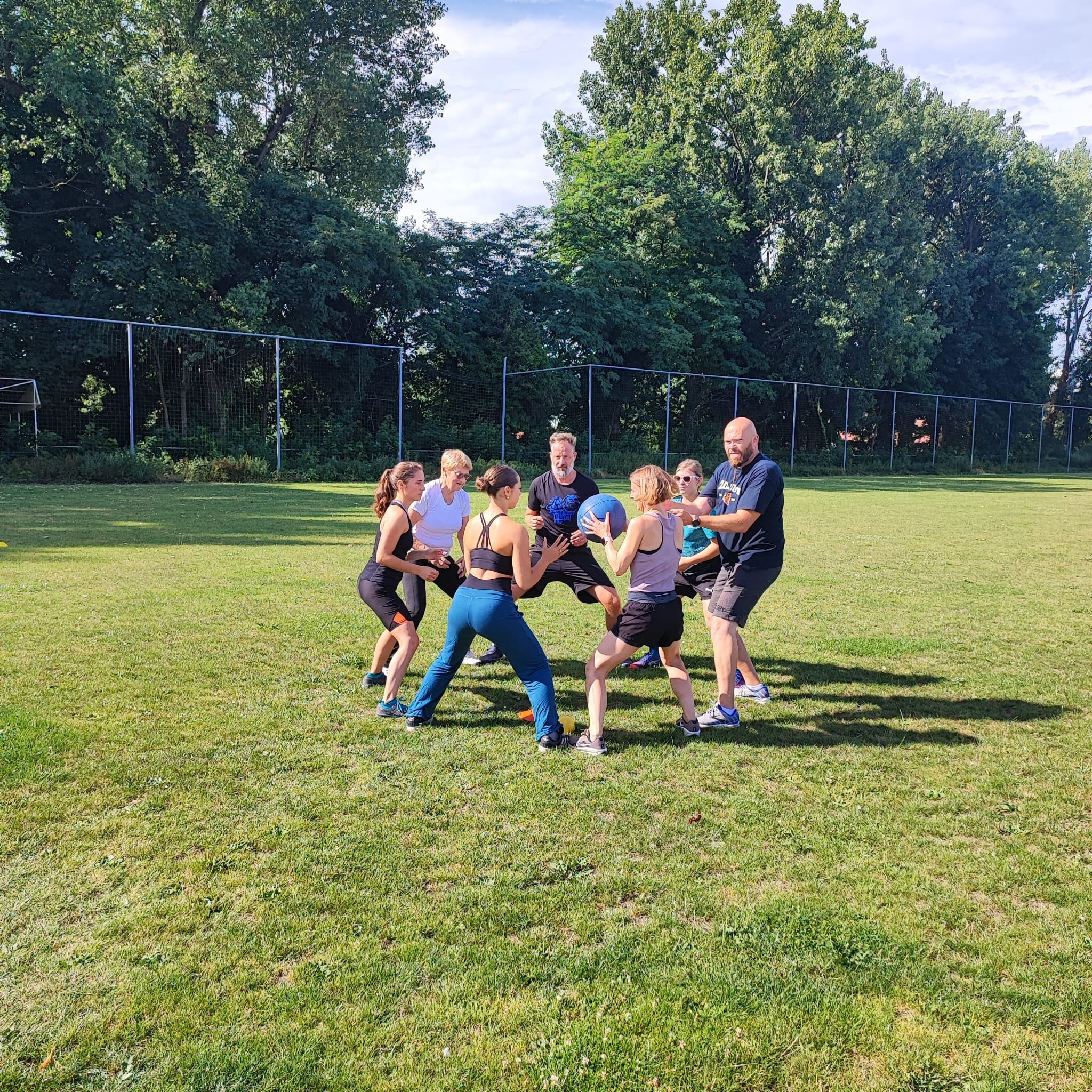 Een groep deelnemers doet samen een actieve bootcamp-oefening op het gras